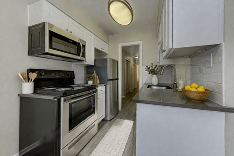 A modern kitchen with a black stove top oven and a silver microwave above it.