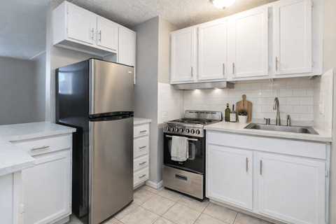 A kitchen with white cabinets and a stainless steel refrigerator.