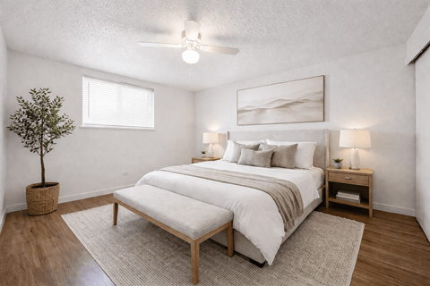 A bedroom with a large bed and a small tree in a pot.