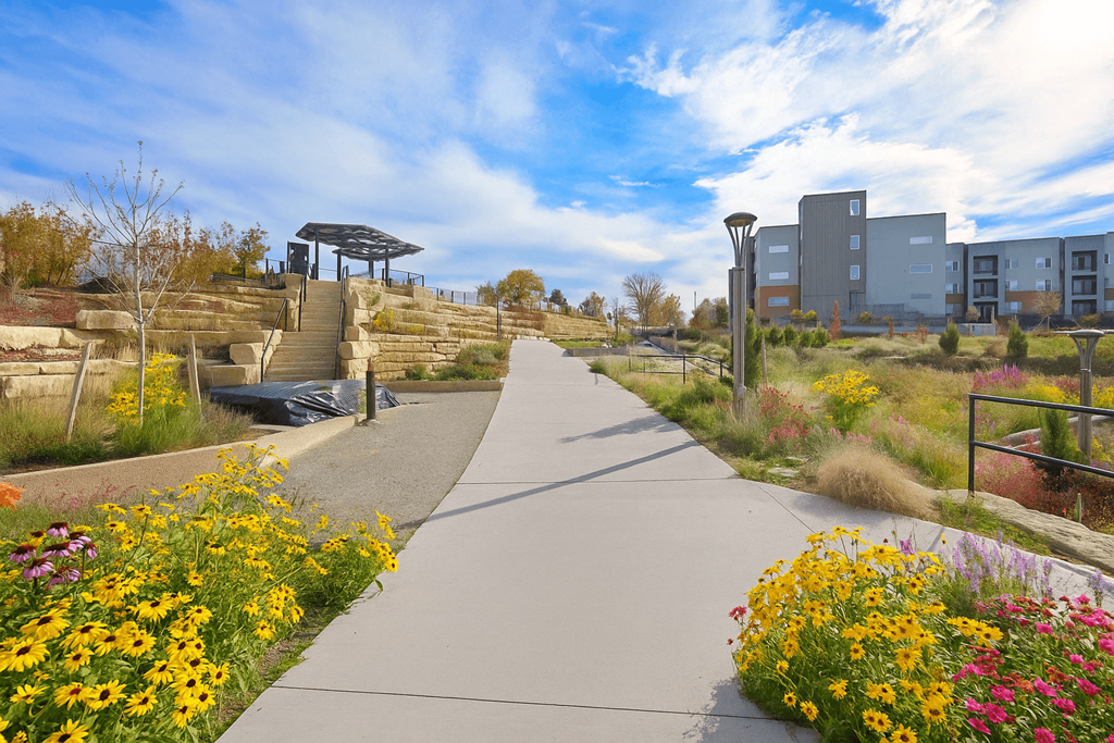 A walkway with a metal railing on the left and a building in the background.