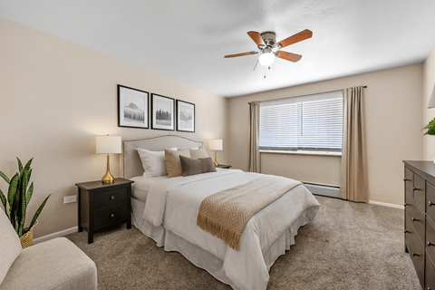 A bedroom with a large bed, a ceiling fan, and a chair.
