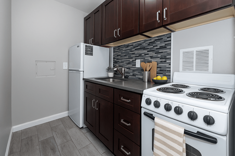 A kitchen with a white refrigerator, a white stove, and brown cabinets.