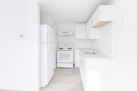 A white kitchen with a refrigerator, oven, and sink.