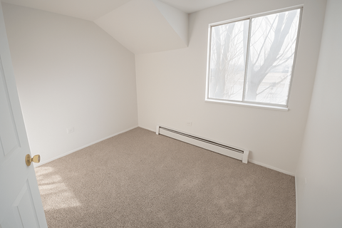 A room with a window and a carpeted floor.