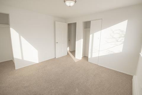 A room with a carpeted floor and a doorway leading to another room.