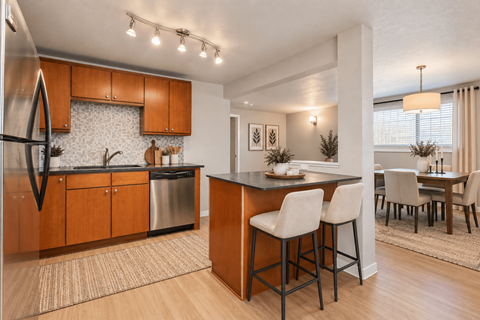 A modern kitchen with wooden cabinets and a bar area.
