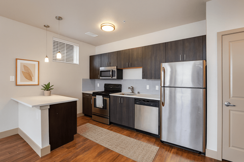 A kitchen with a refrigerator, microwave, and oven.