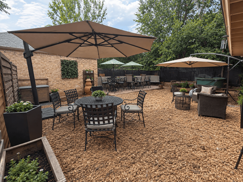 A patio with a table and chairs under an umbrella.