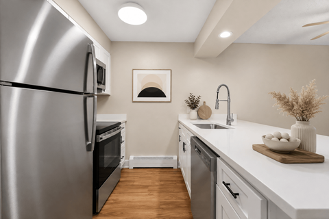 A modern kitchen with a stainless steel refrigerator and wooden flooring.