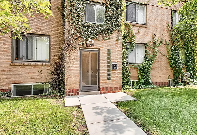 the front door of a brick house with ivy on it