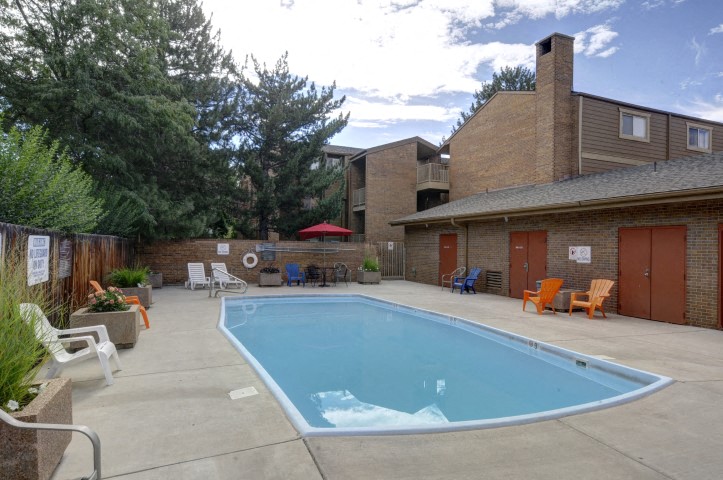 A small pool in a backyard with a patio and chairs.