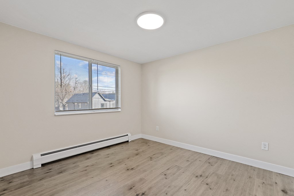 an empty living room with wood flooring and a window