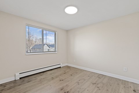 an empty living room with wood flooring and a window