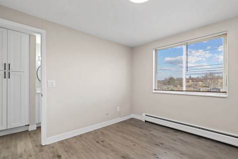 the living room of an apartment with wood flooring and a large window