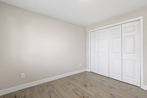 an empty room with white doors and a wood floor