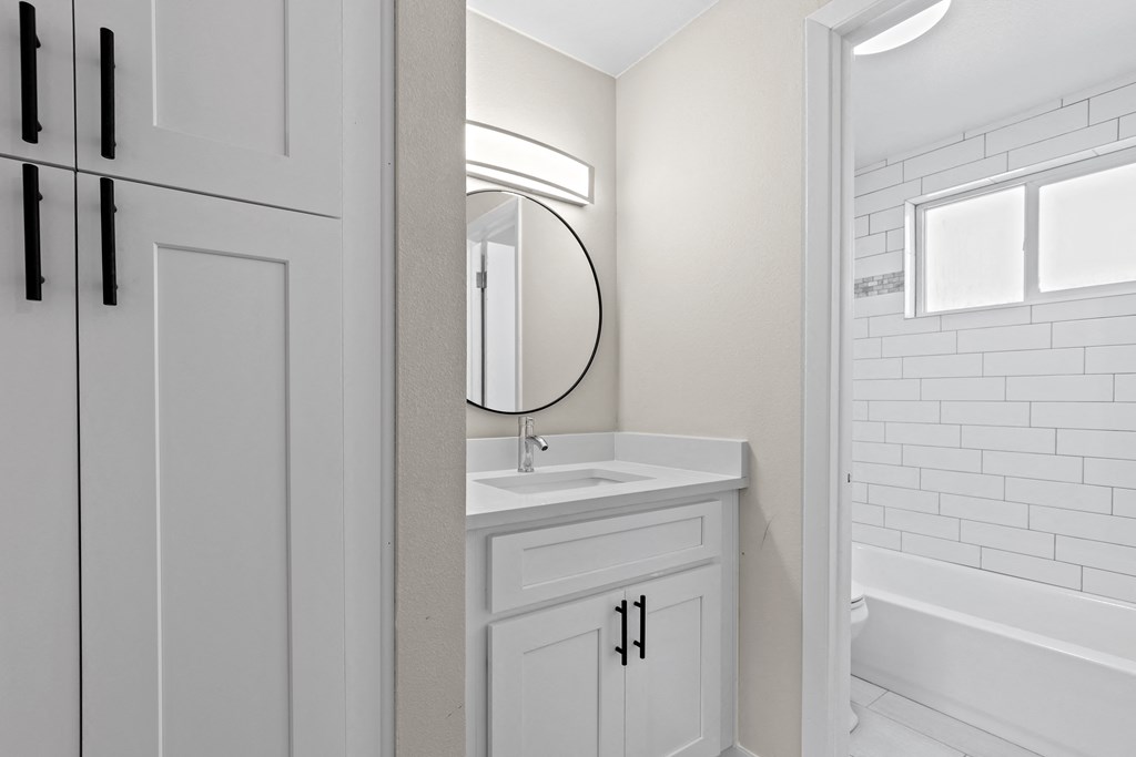 a white bathroom with a white sink and a mirror