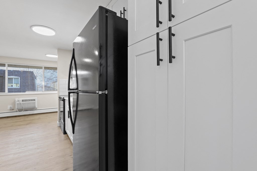 a kitchen with white cabinets and a black refrigerator