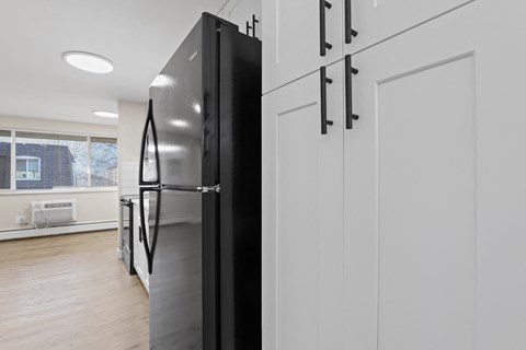 a kitchen with white cabinets and a black refrigerator
