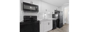 a kitchen with white cabinets and black appliances and a black refrigerator