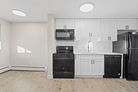 a kitchen with white cabinets and black appliances and a refrigerator