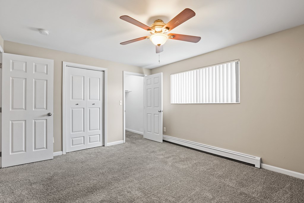 A room with a ceiling fan and three doors.