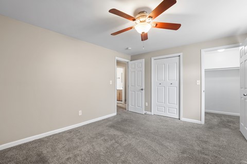 A room with a ceiling fan and carpeted floor.