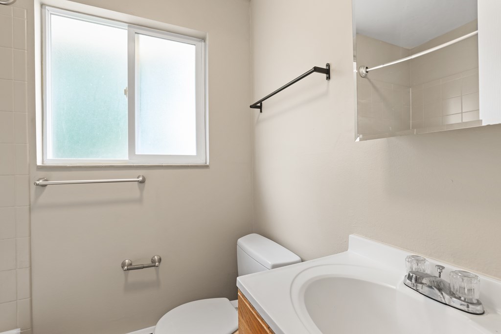 A white toilet sits next to a white sink in a bathroom.