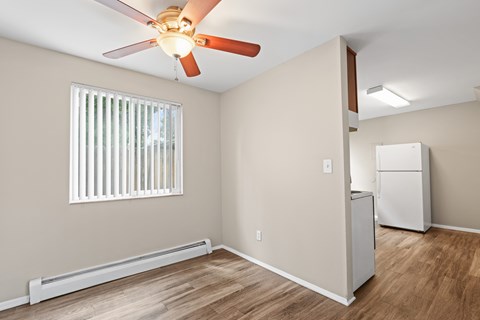A room with a ceiling fan and a window with blinds.