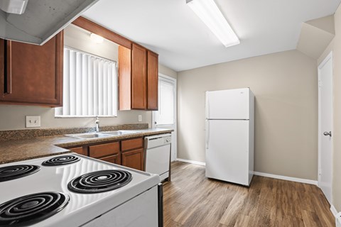 A kitchen with a white stove top oven and wooden cabinets.