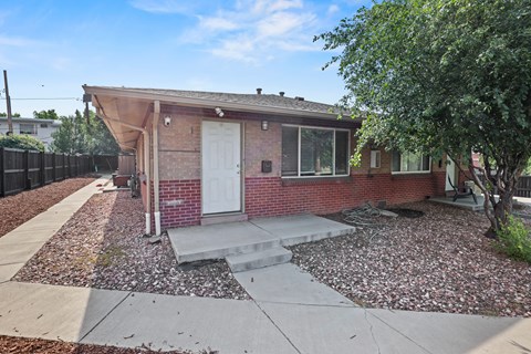 A red brick house with a white door and a small porch.