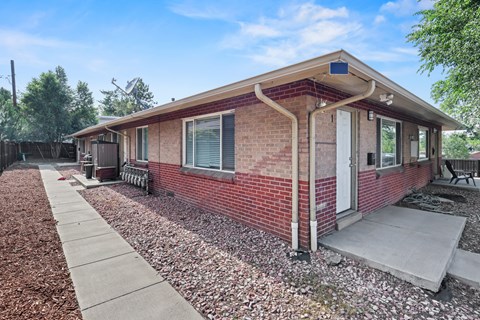 A red brick house with a white door and a small porch.