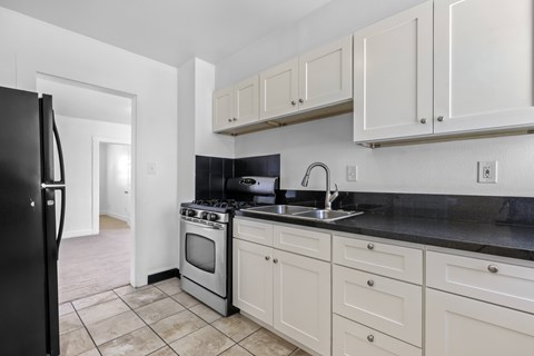 A kitchen with white cabinets and black countertops.