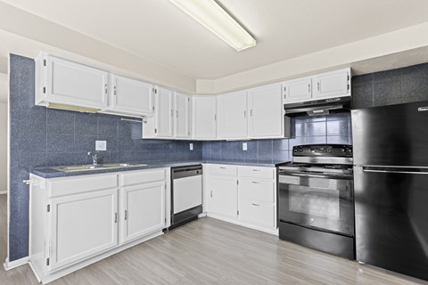 A kitchen with white cabinets and a black refrigerator.