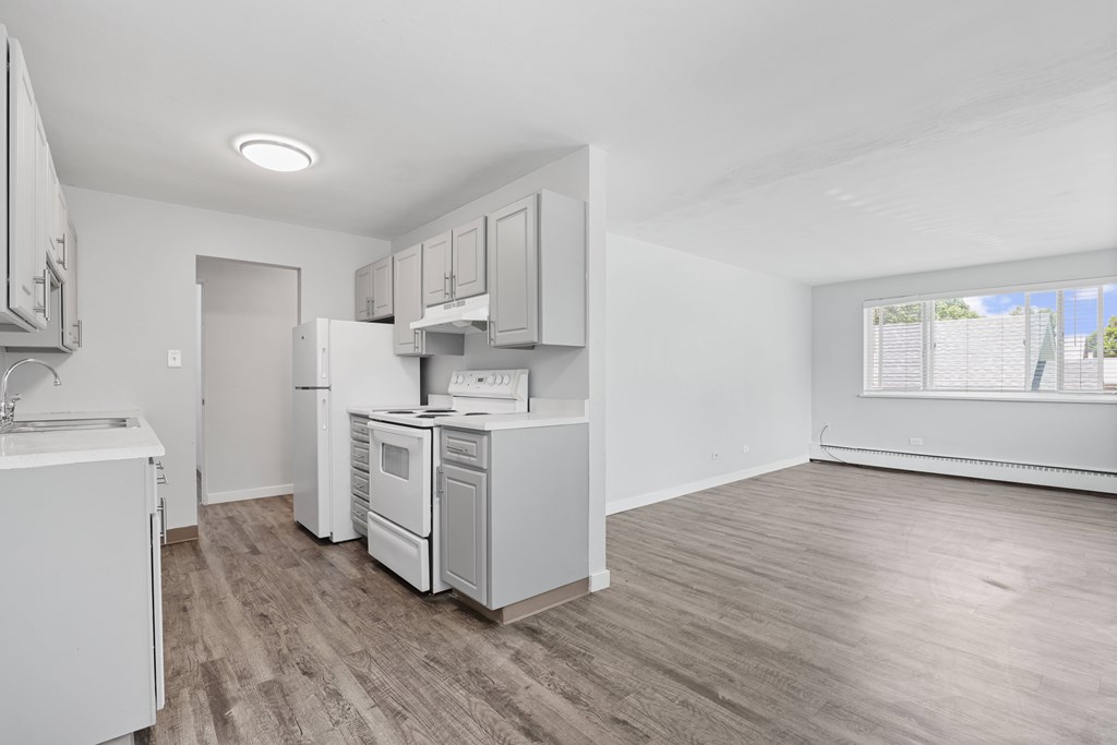 A kitchen with white appliances and wooden floors.