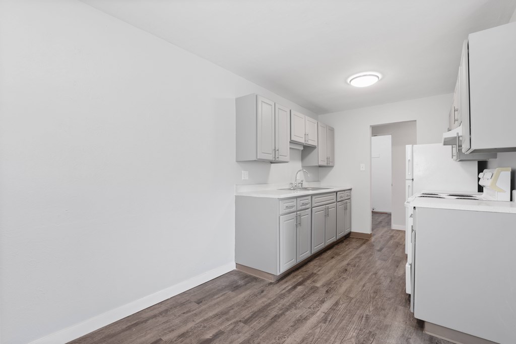 A kitchen with white cabinets and a refrigerator.