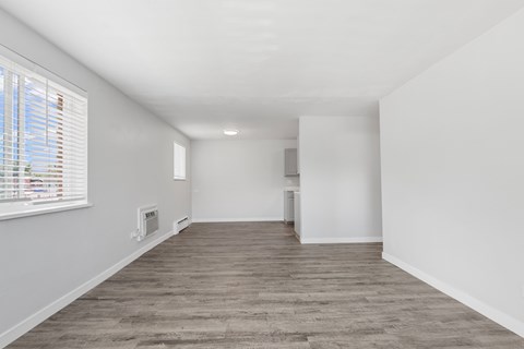 A room with a window on the left and a wooden floor.