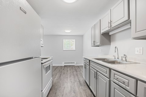 A kitchen with a white refrigerator and a window with blinds.