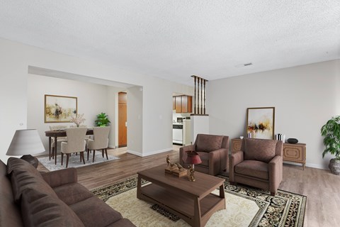 A living room with a brown couch, a coffee table, and a dining table with chairs.
