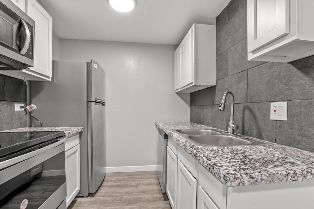A kitchen with a granite countertop and stainless steel appliances.