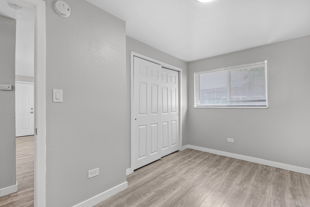 A room with a white door and a window with blinds.