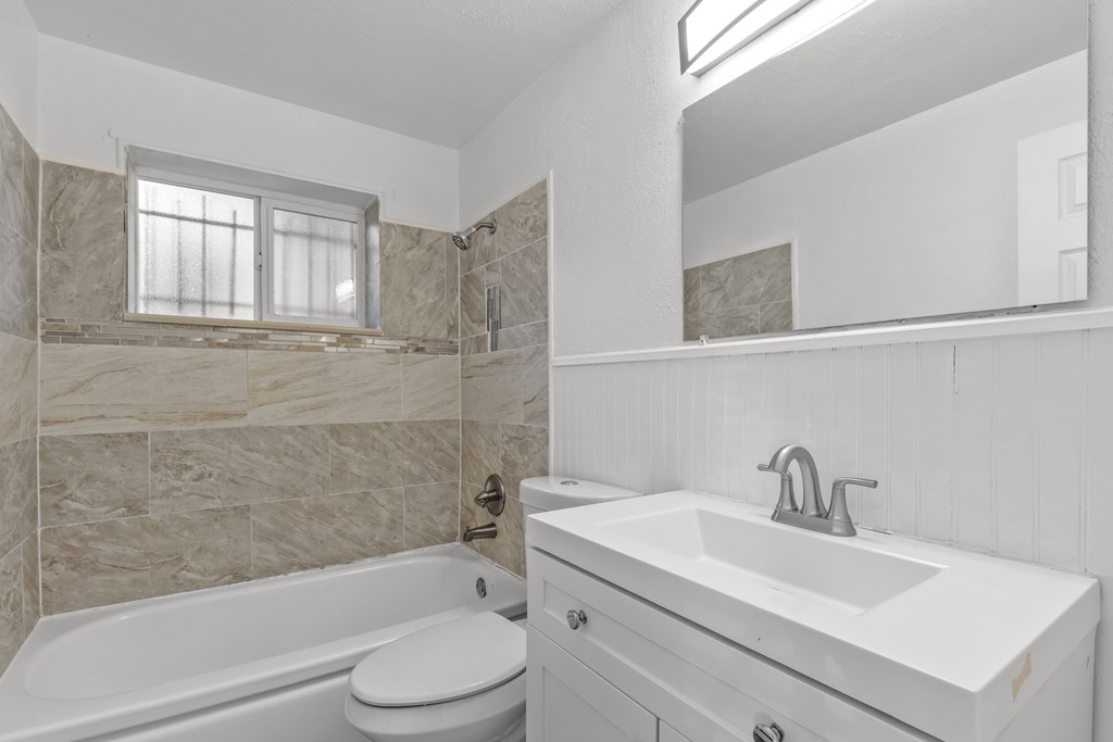 A white bathroom with a tub, sink, and mirror.