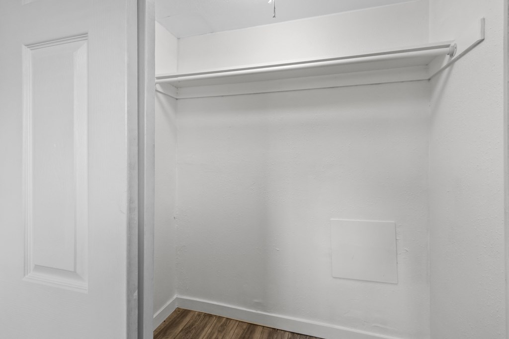 A white closet with a shelf and a door.