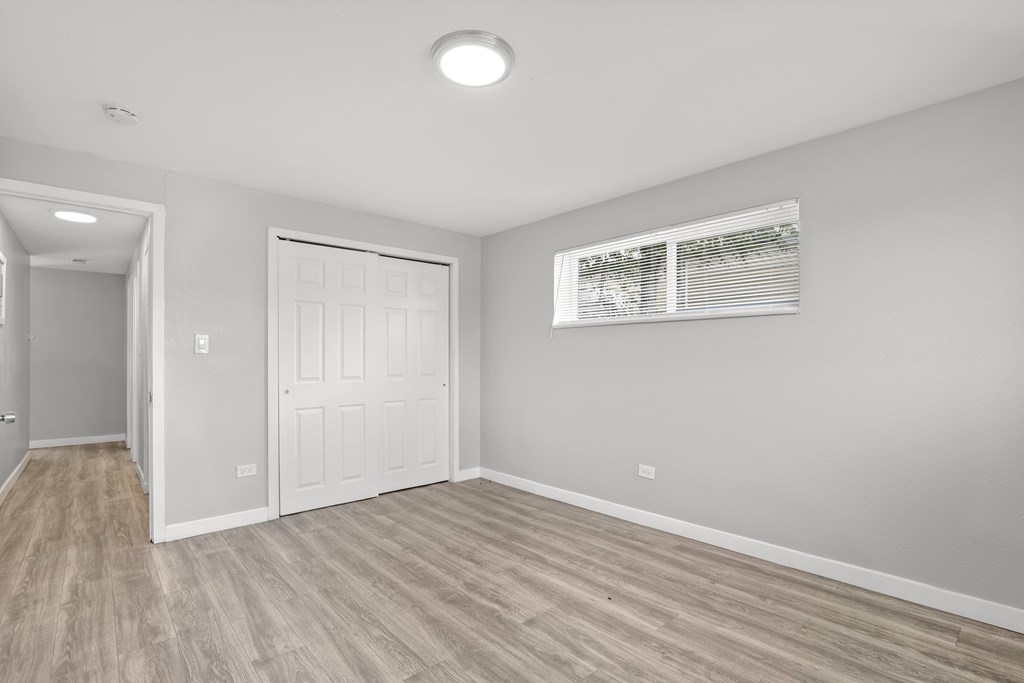 A room with a white door and a window with blinds.