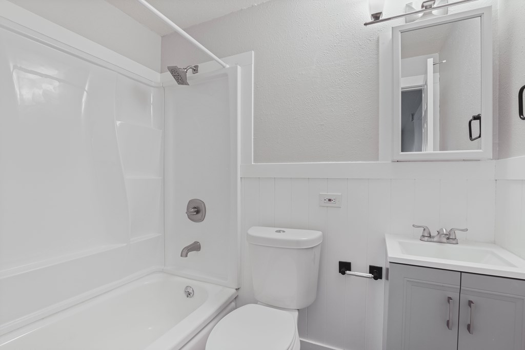 A white bathroom with a toilet, sink, and bathtub.