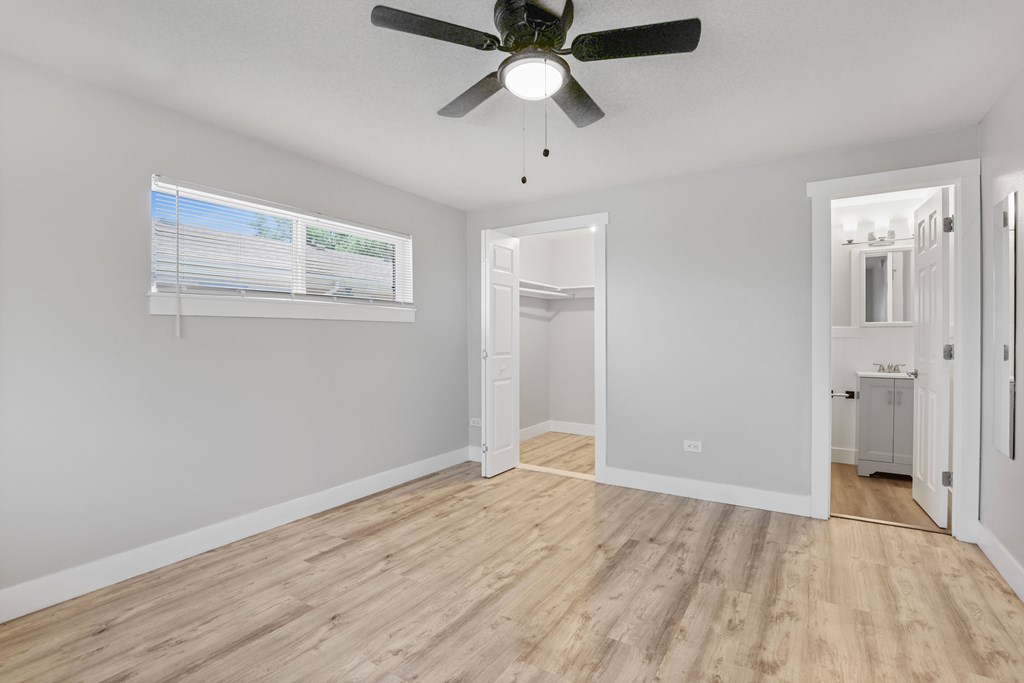 A room with a ceiling fan and wooden flooring.