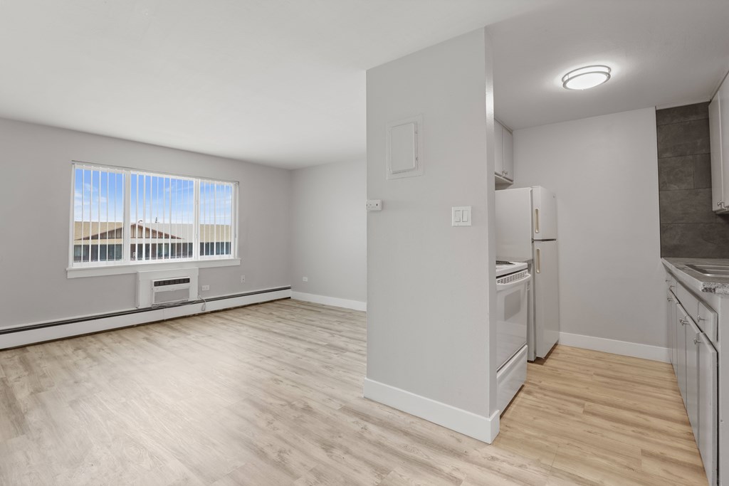 A kitchen with white appliances and wooden floors.