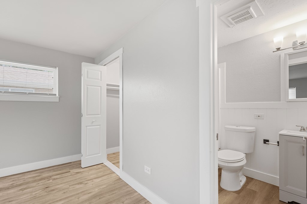 A white bathroom with a toilet, sink, and mirror.
