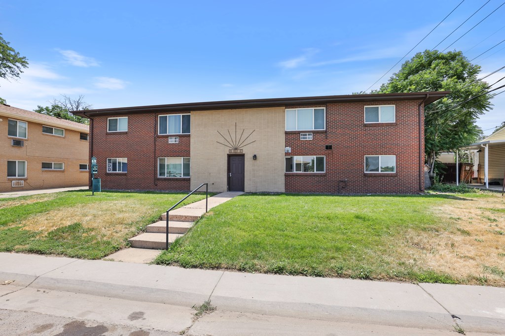 A brick apartment building with a green lawn in front.