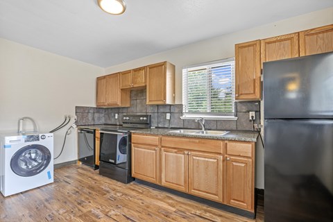 A kitchen with wooden cabinets and a black refrigerator.