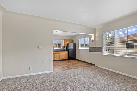 A spacious living room with a kitchen in the background.